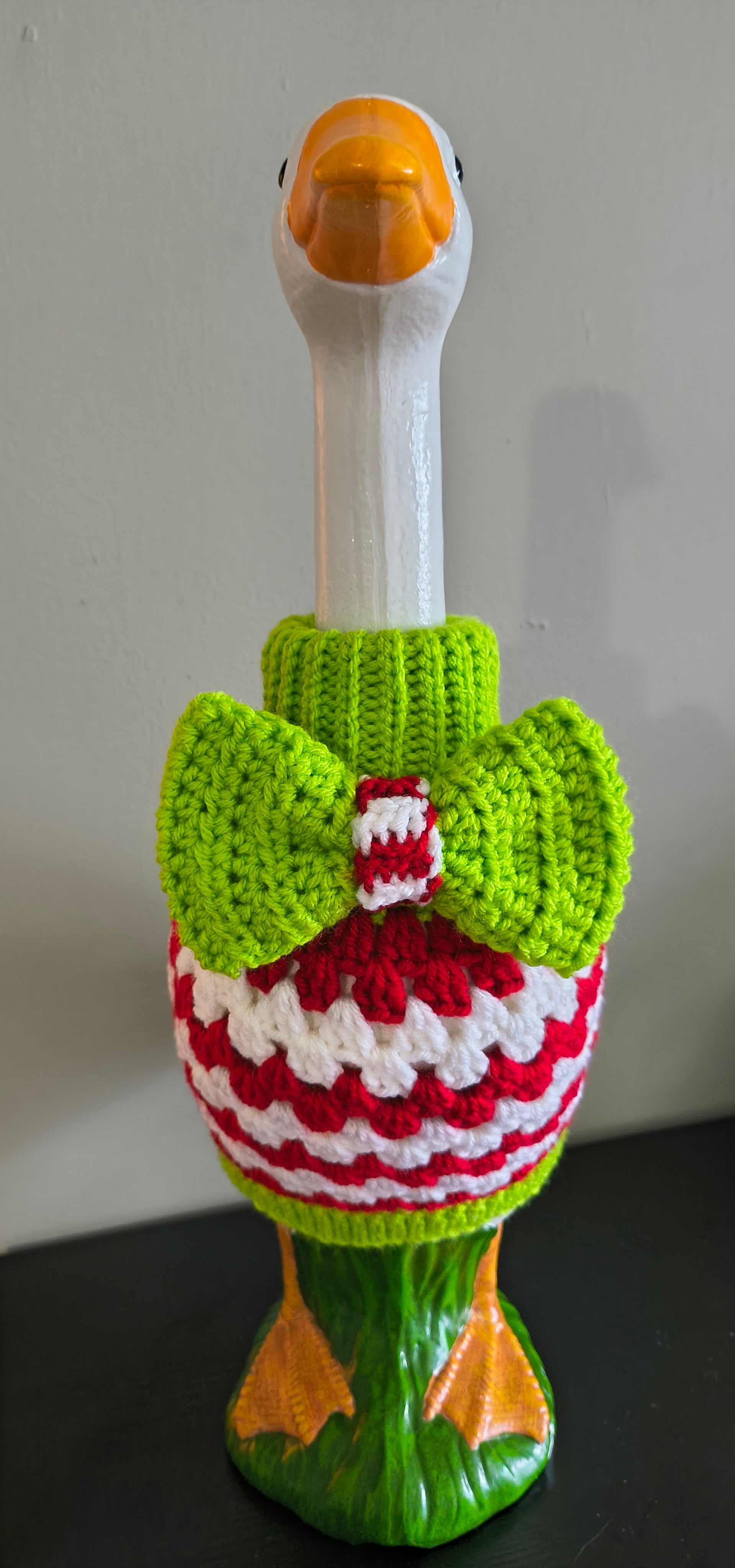 Handmade lime green and red crochet turtleneck sweater with bow on head of porch goose, back view