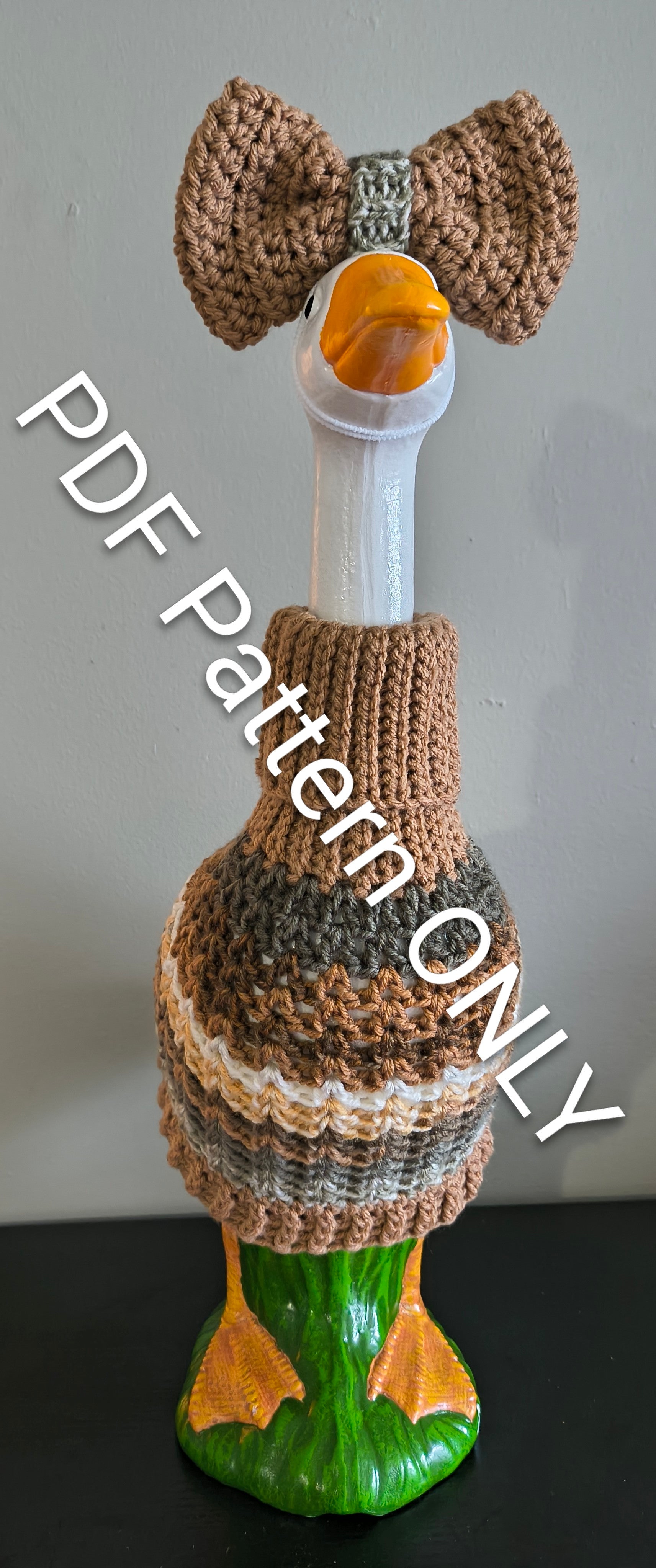 Pink crochet porch goose sweater with bow on goose statue - front view