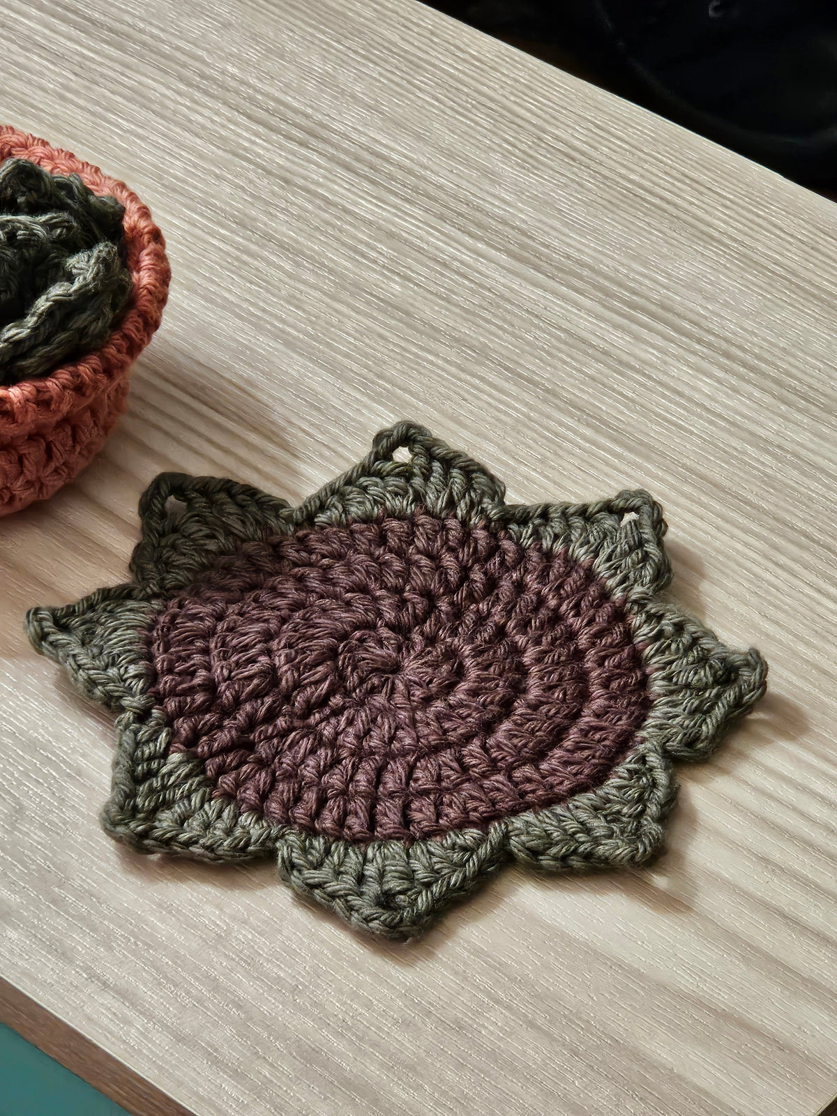Crochet succulent leaf coaster in mauve and olive green - close up flat lay